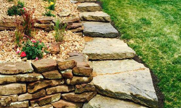 A hand-laid Colorado moss-rock drystack wall with intact lichen patina across the field stones.