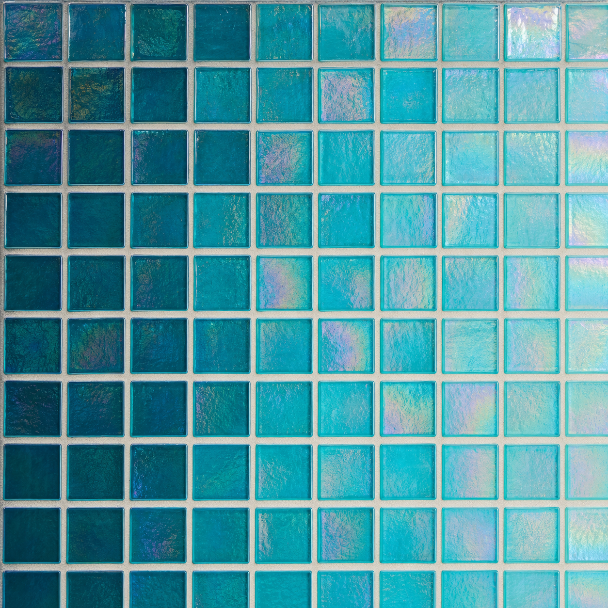 An iridescent Italian glass mosaic tile in a pearlescent teal-to-turquoise finish that shifts color with the angle of light.